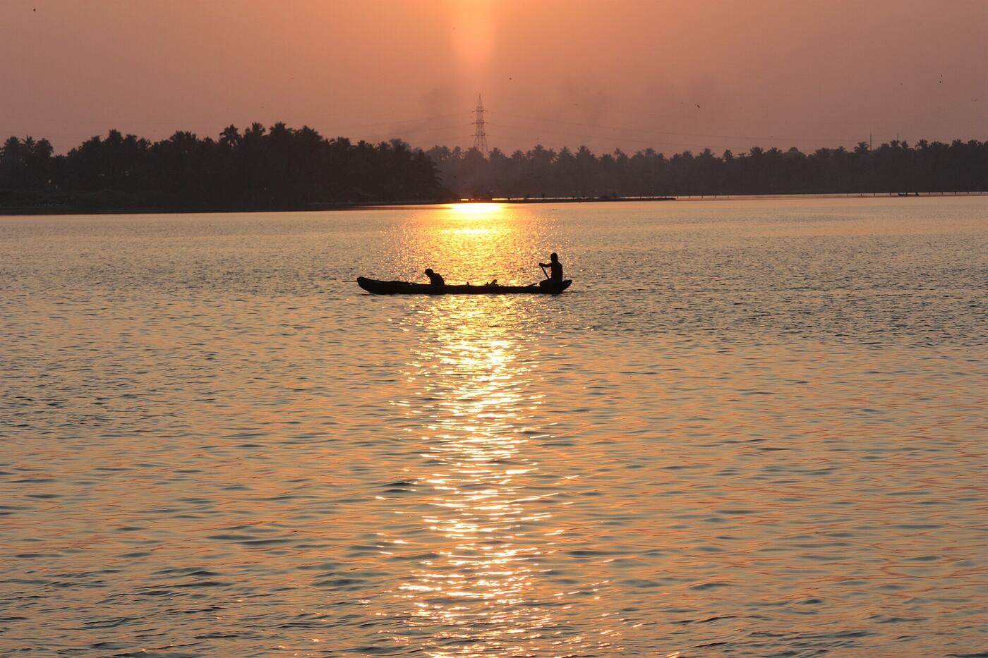 A country canoe silhouetted against the sunset on the Kerala backwaters