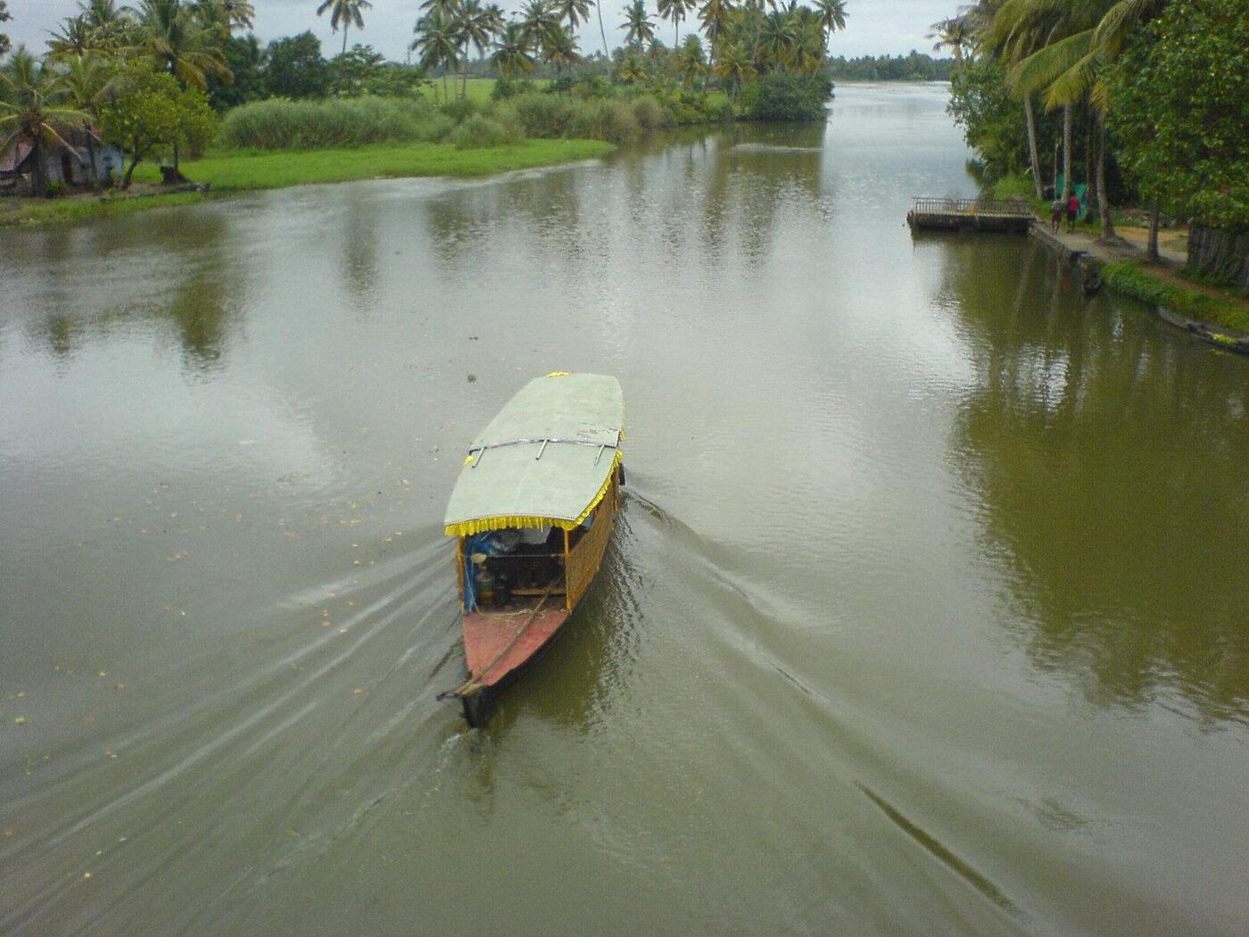 A country canoe on a narrow canal past a Kerala backwater village